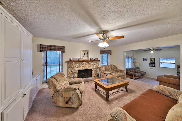 carpeted living room featuring a fireplace, ceiling fan, and a textured ceiling