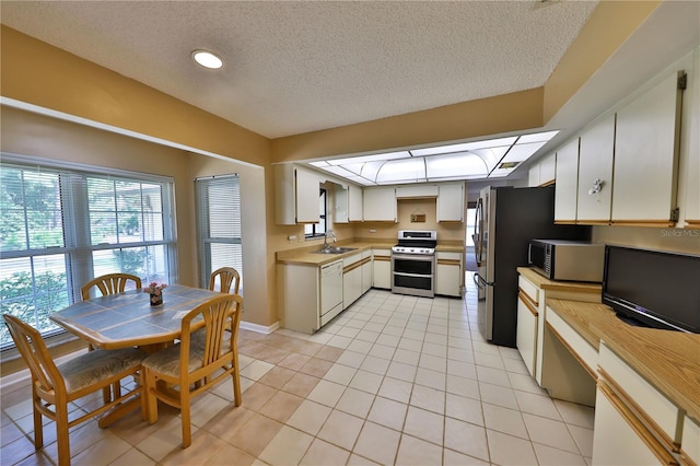 kitchen with light tile patterned floors, sink, a textured ceiling, white cabinetry, and appliances with stainless steel finishes