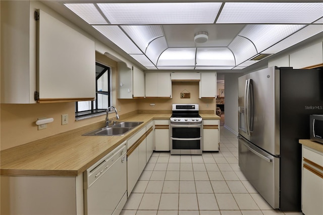 kitchen featuring light tile patterned flooring, appliances with stainless steel finishes, sink, and white cabinetry