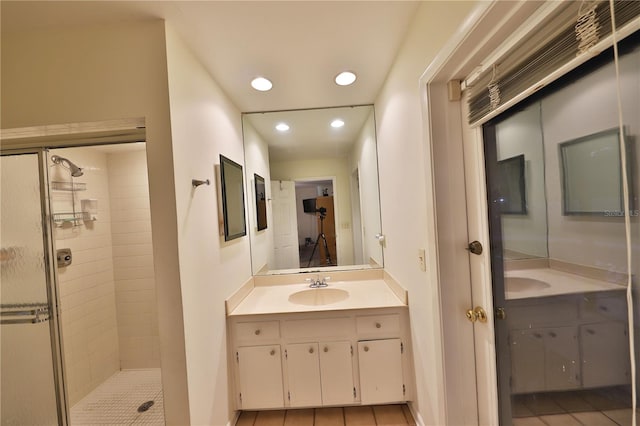 bathroom featuring tile patterned flooring, a tile shower, and vanity