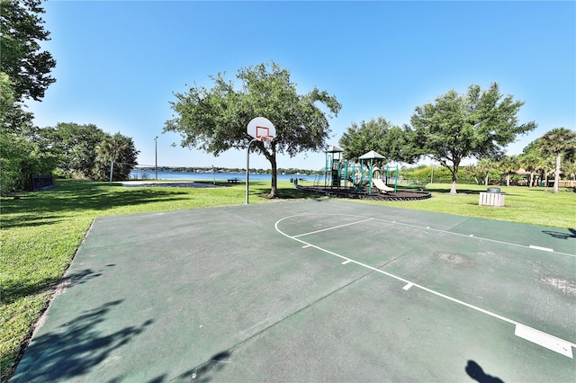 view of basketball court with a playground, a water view, and a lawn