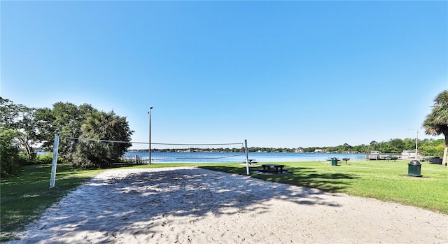 view of community featuring a lawn, a water view, and volleyball court