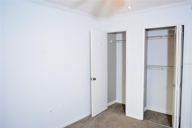 unfurnished bedroom with ornamental molding, carpet floors, and multiple closets