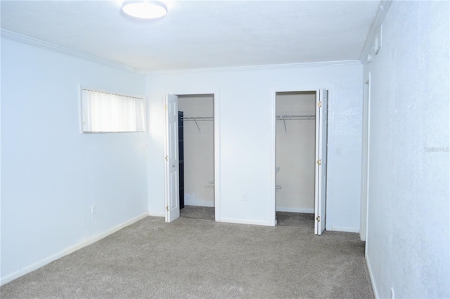 unfurnished bedroom featuring crown molding, light carpet, and two closets