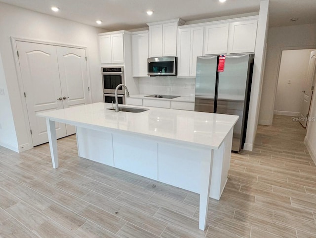 kitchen featuring white cabinets, an island with sink, stainless steel appliances, and sink