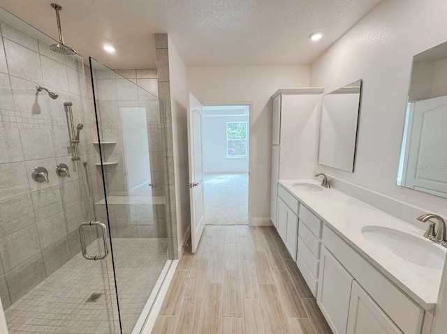 bathroom with walk in shower, vanity, and a textured ceiling