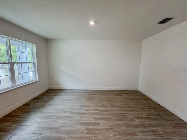 empty room with light wood-type flooring and a textured ceiling