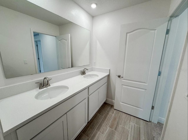 2949 Sunset Dr, New Smyrna Beach, FL 32168 - full bath with wood finish floors, double vanity, a sink, and baseboards