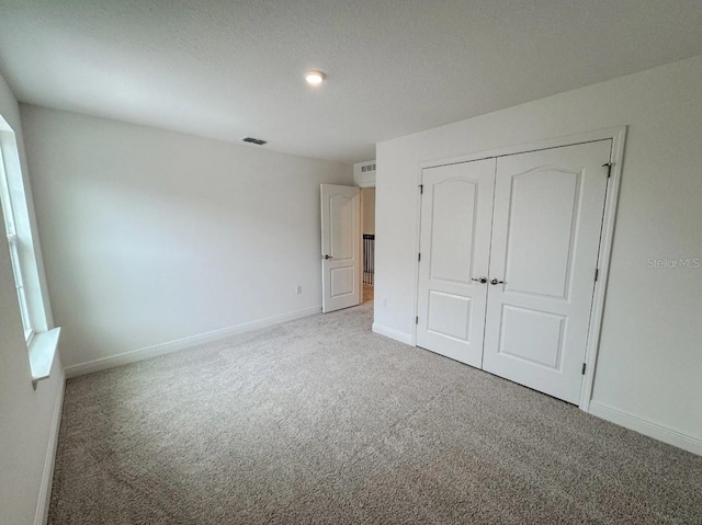 unfurnished bedroom featuring a textured ceiling, a closet, and carpet flooring