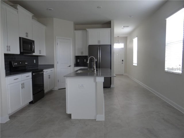 kitchen with black range with electric stovetop, white cabinets, a center island with sink, and tasteful backsplash