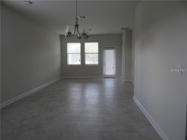 unfurnished dining area with dark tile patterned floors and a chandelier