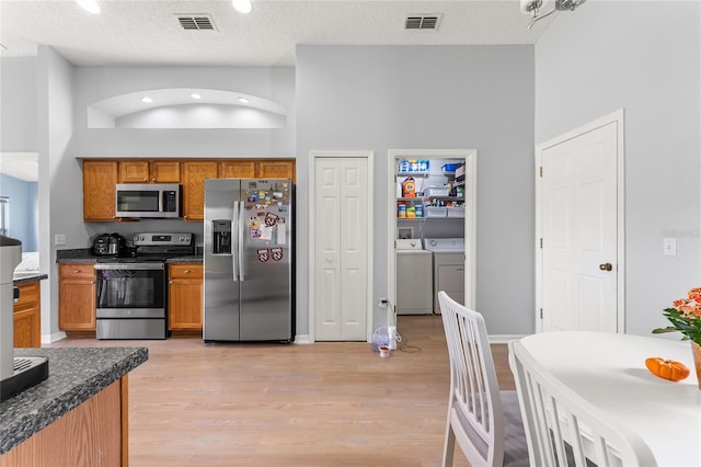 kitchen with a textured ceiling, stainless steel appliances, and a high ceiling