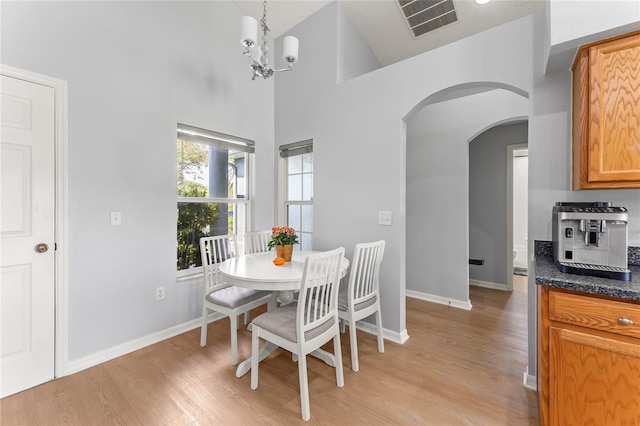 dining space featuring light hardwood / wood-style floors, high vaulted ceiling, a notable chandelier, and a textured ceiling