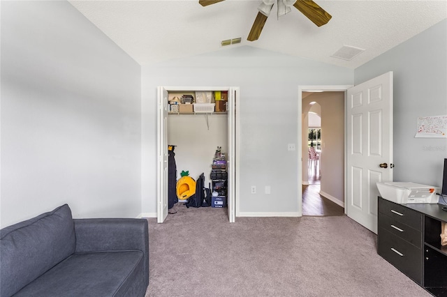 interior space featuring a textured ceiling, ceiling fan, vaulted ceiling, and carpet flooring