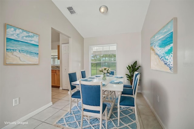 tiled dining area with lofted ceiling and sink