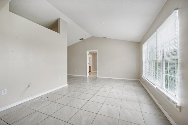 unfurnished room featuring lofted ceiling, plenty of natural light, and light tile patterned floors