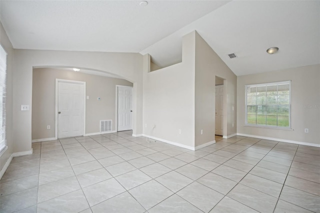 empty room featuring lofted ceiling and light tile patterned floors