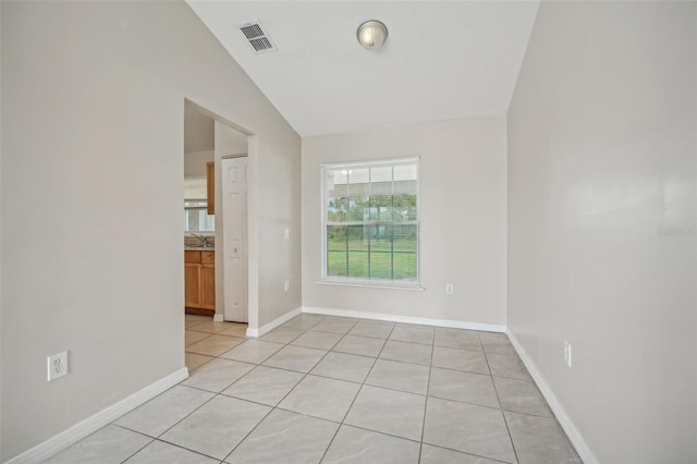 tiled spare room with sink and vaulted ceiling