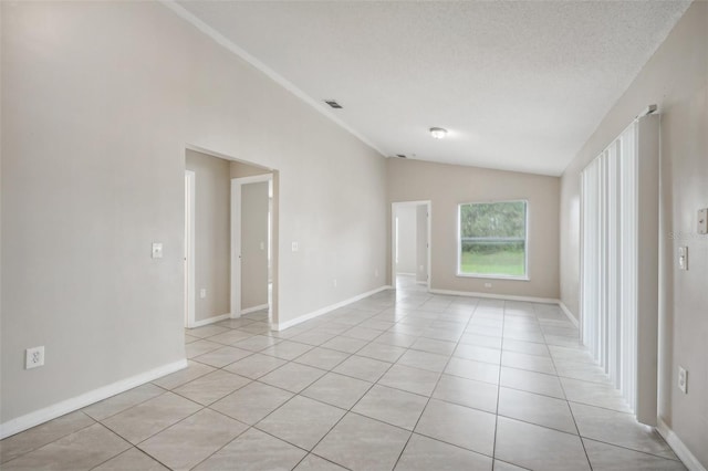 tiled spare room featuring lofted ceiling and a textured ceiling