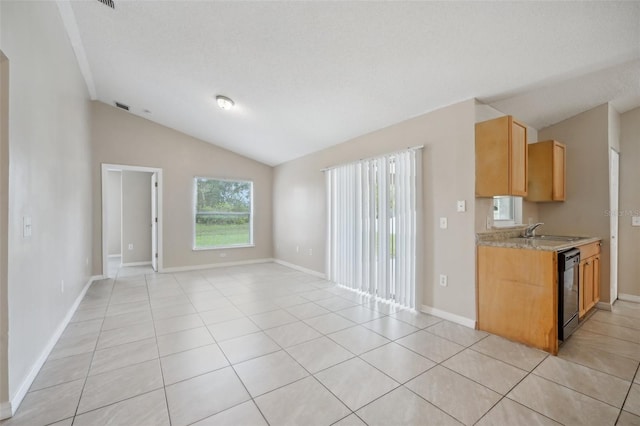 kitchen with light tile patterned flooring, vaulted ceiling, sink, dishwasher, and a textured ceiling