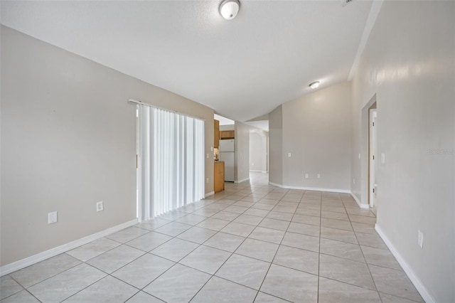 tiled spare room with vaulted ceiling