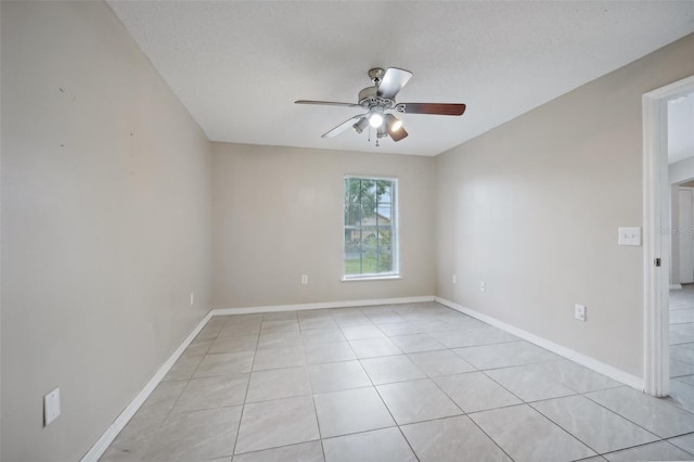 spare room featuring ceiling fan, light tile patterned flooring, and a textured ceiling