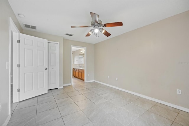 unfurnished bedroom featuring ceiling fan, a closet, ensuite bath, and light tile patterned floors