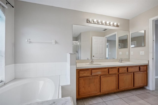 bathroom with tile patterned floors, a tub to relax in, and vanity