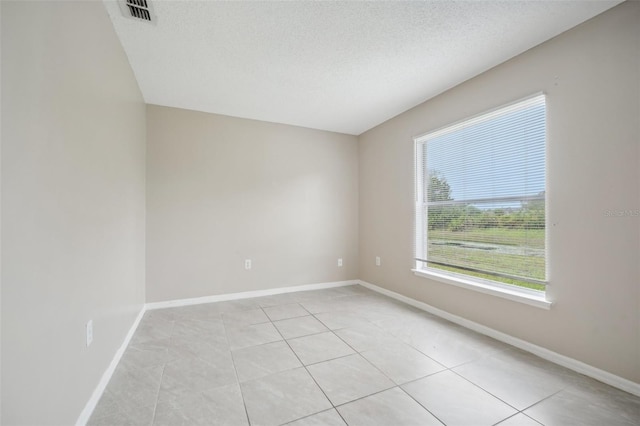 empty room with a textured ceiling and light tile patterned floors