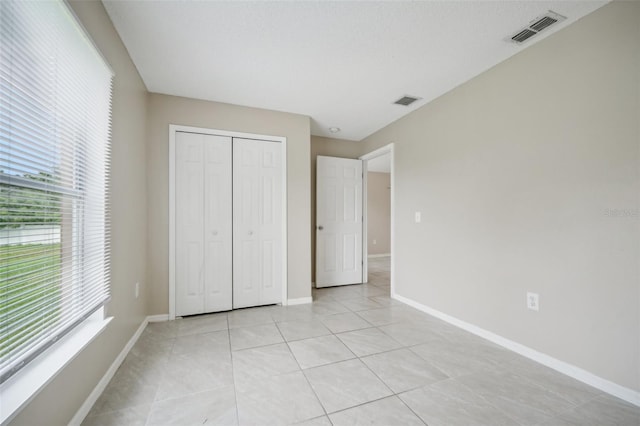 unfurnished bedroom featuring a closet and light tile patterned floors