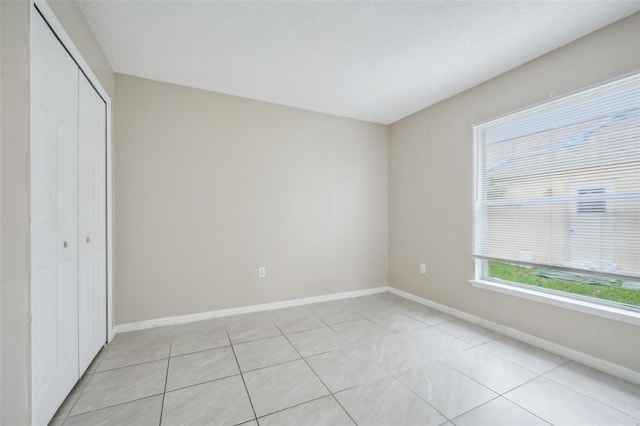 unfurnished bedroom featuring light tile patterned flooring, a closet, and a textured ceiling