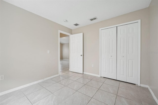 unfurnished bedroom featuring light tile patterned flooring, a closet, and a textured ceiling