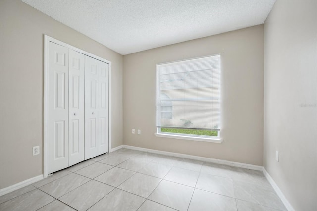 unfurnished bedroom featuring a closet, light tile patterned floors, and a textured ceiling