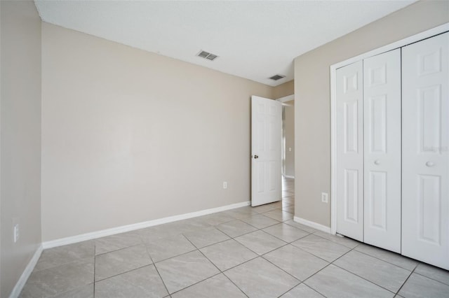 unfurnished bedroom featuring a textured ceiling, a closet, and light tile patterned floors