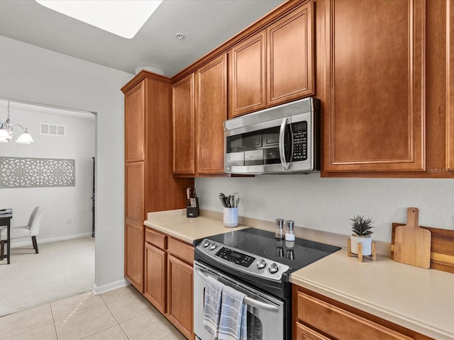 kitchen featuring stainless steel appliances, an inviting chandelier, decorative light fixtures, light tile patterned floors, and a textured ceiling