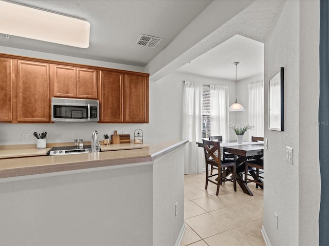 kitchen with pendant lighting, appliances with stainless steel finishes, and light tile patterned floors