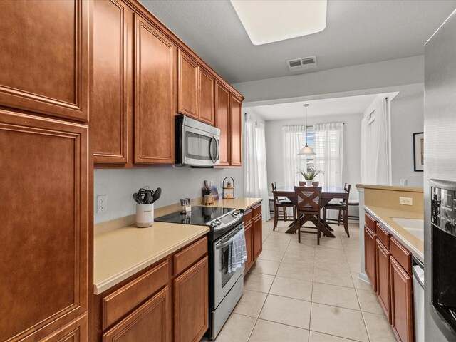 kitchen with stainless steel appliances, pendant lighting, and light tile patterned floors