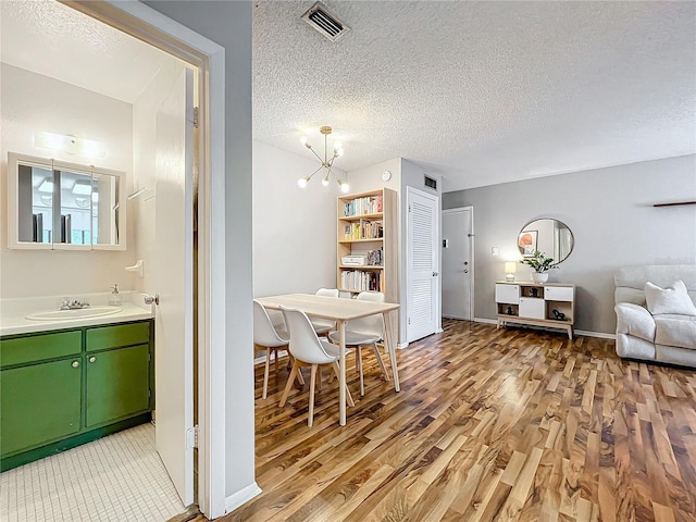 dining area featuring light hardwood / wood-style floors, a textured ceiling, sink, and an inviting chandelier