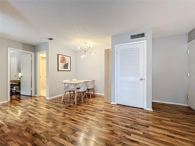 dining space featuring a textured ceiling, a notable chandelier, and hardwood / wood-style flooring