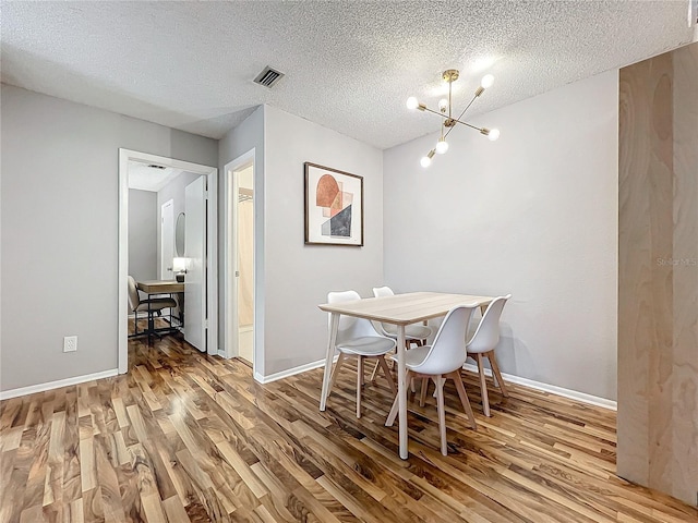 dining room with a notable chandelier, hardwood / wood-style flooring, and a textured ceiling