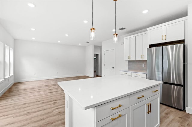 kitchen with a kitchen island, hanging light fixtures, light hardwood / wood-style floors, white cabinets, and stainless steel refrigerator