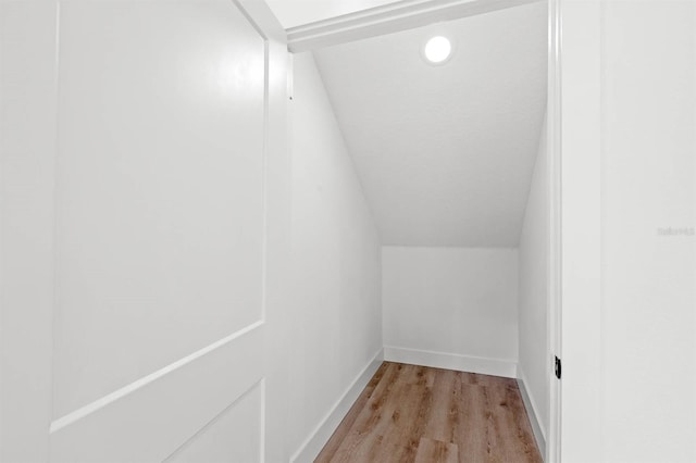 walk in closet with light hardwood / wood-style floors and vaulted ceiling