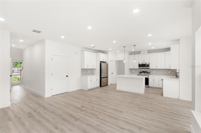 634 Burch Ave, Winter Garden, FL 34787 - kitchen featuring appliances with stainless steel finishes, a kitchen island, backsplash, light wood-style flooring, and recessed lighting