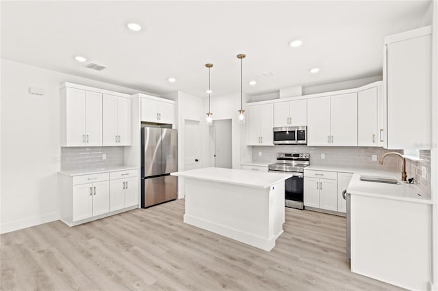 634 Burch Ave, Winter Garden, FL 34787 - kitchen featuring stainless steel appliances, a sink, a kitchen island, decorative backsplash, and light wood-style flooring