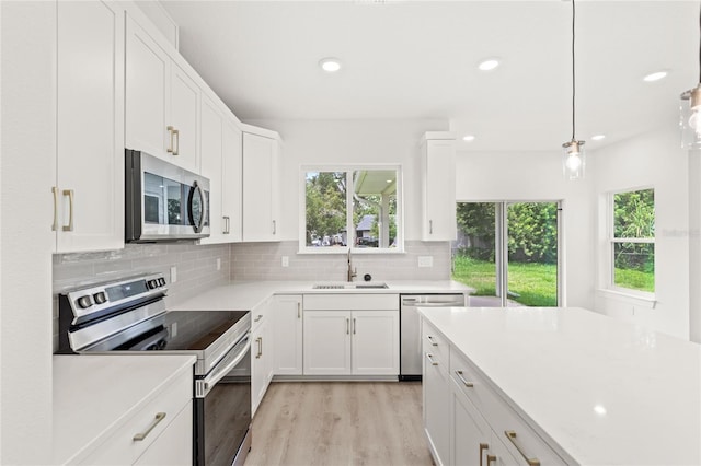 634 Burch Ave, Winter Garden, FL 34787 - kitchen with appliances with stainless steel finishes, a sink, light wood finished floors, light countertops, and white cabinetry