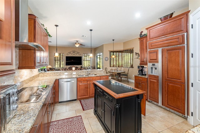 kitchen with ceiling fan, sink, wall chimney exhaust hood, appliances with stainless steel finishes, and light stone countertops