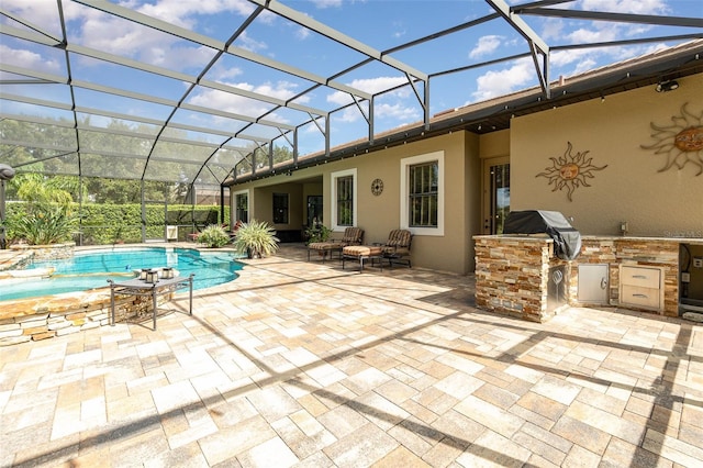 view of pool featuring a patio, glass enclosure, an outdoor kitchen, and area for grilling