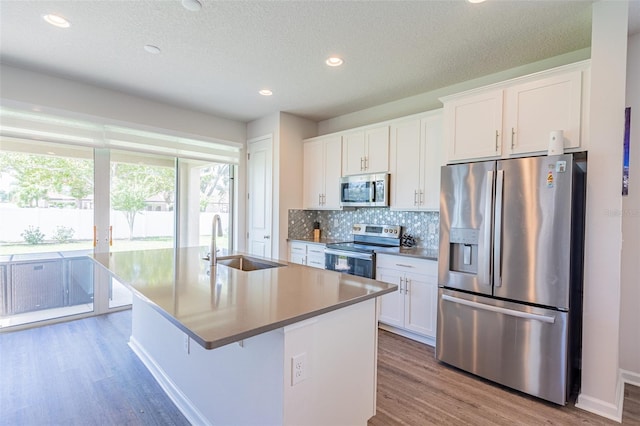 kitchen featuring appliances with stainless steel finishes, sink, an island with sink, and white cabinets