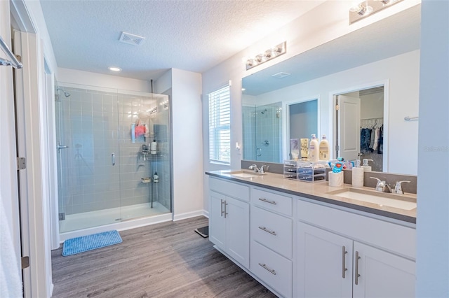 bathroom with vanity, a textured ceiling, hardwood / wood-style floors, and an enclosed shower