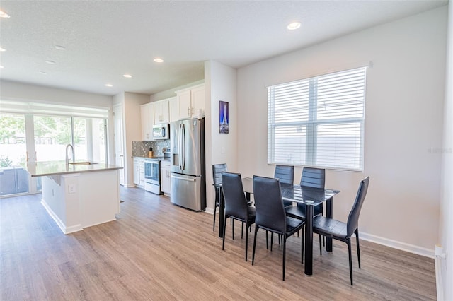 dining room with a textured ceiling, sink, and light hardwood / wood-style flooring